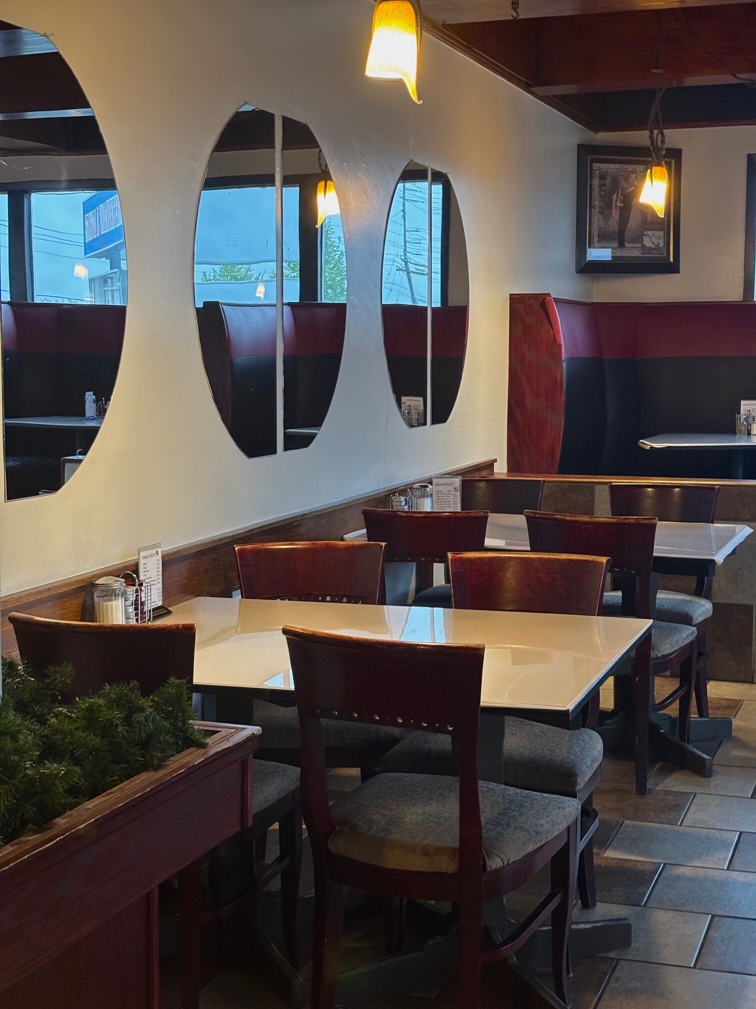 Interior de restaurante con cabinas, mesas y una barra.