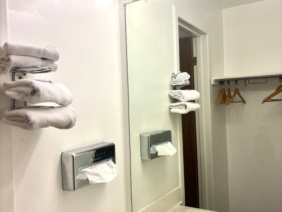 A bathroom with a large mirror, towel rack, and a sink with a faucet.