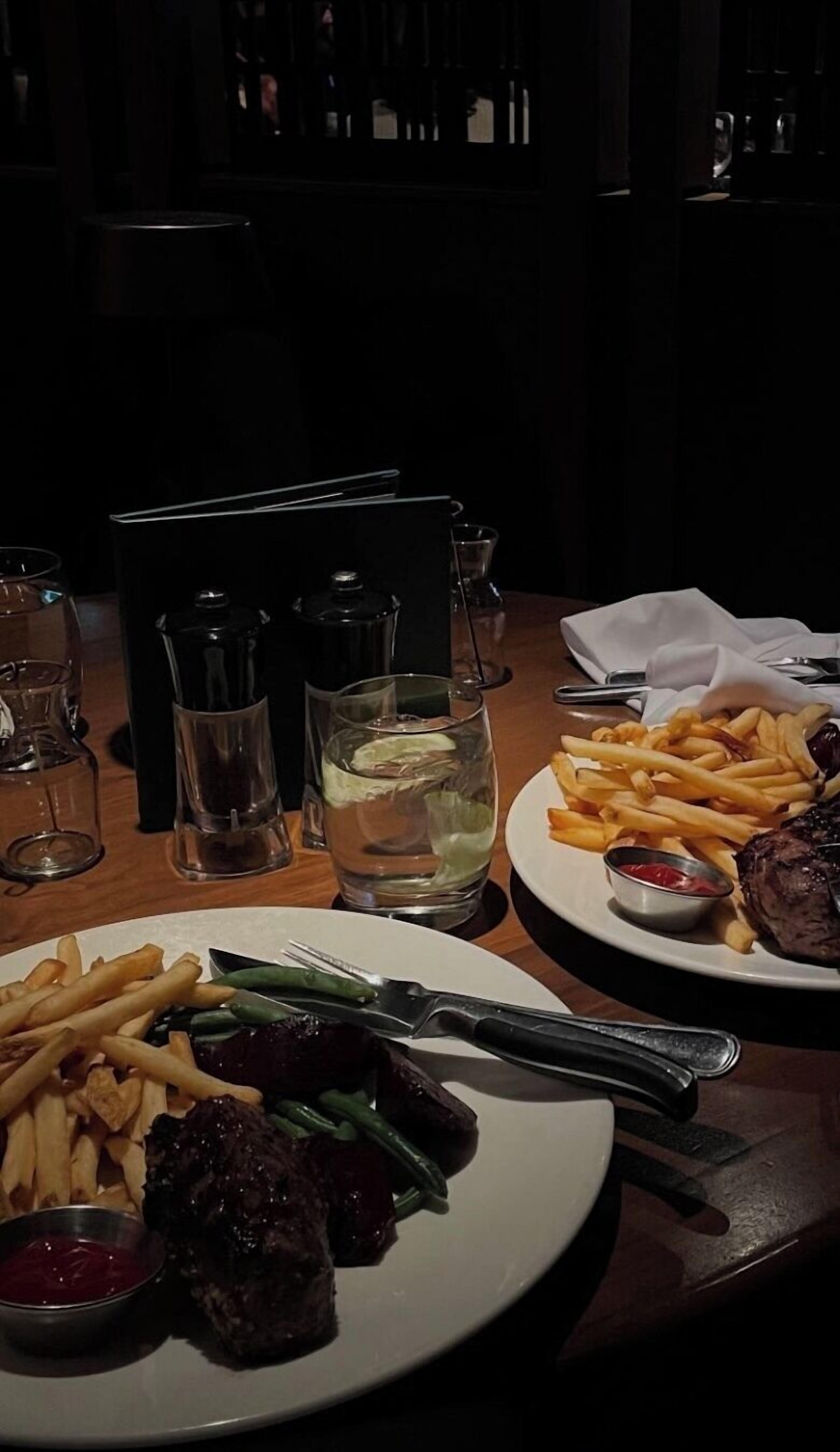 A dining table with plates of food, glasses, and cutlery.