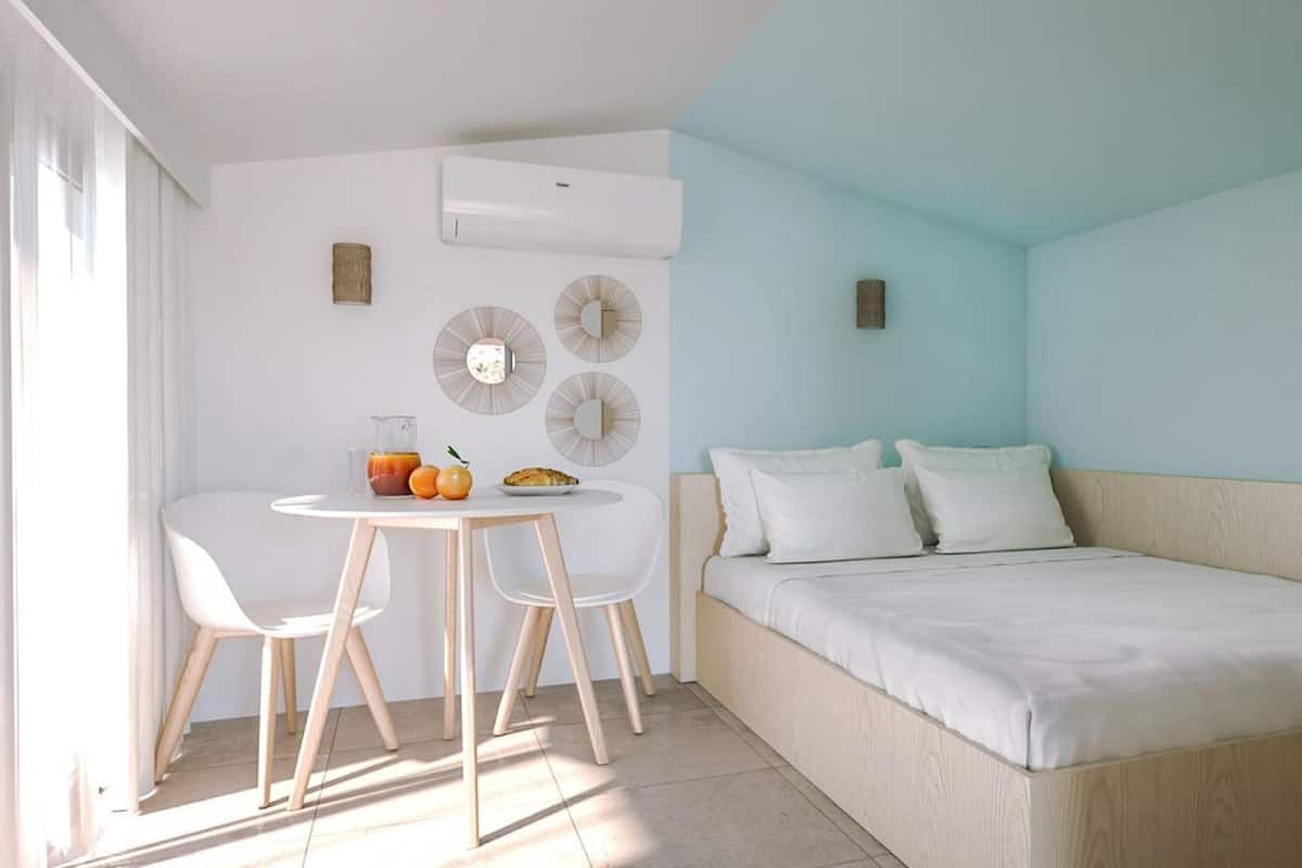 A bedroom with a bed, a small table with chairs, and a breakfast setup.