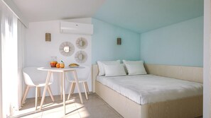 A bedroom with a bed, a small table with chairs, and a breakfast setup.