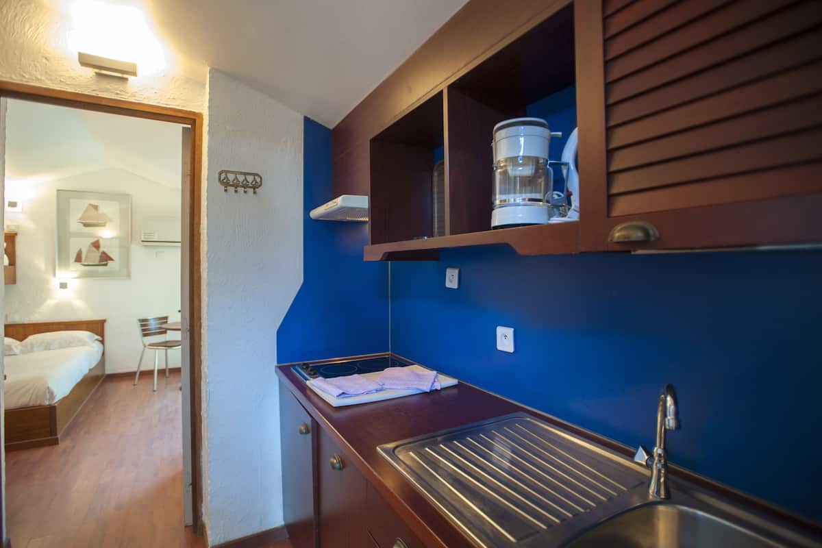 A compact kitchen with a sink, a coffee maker, and a countertop.