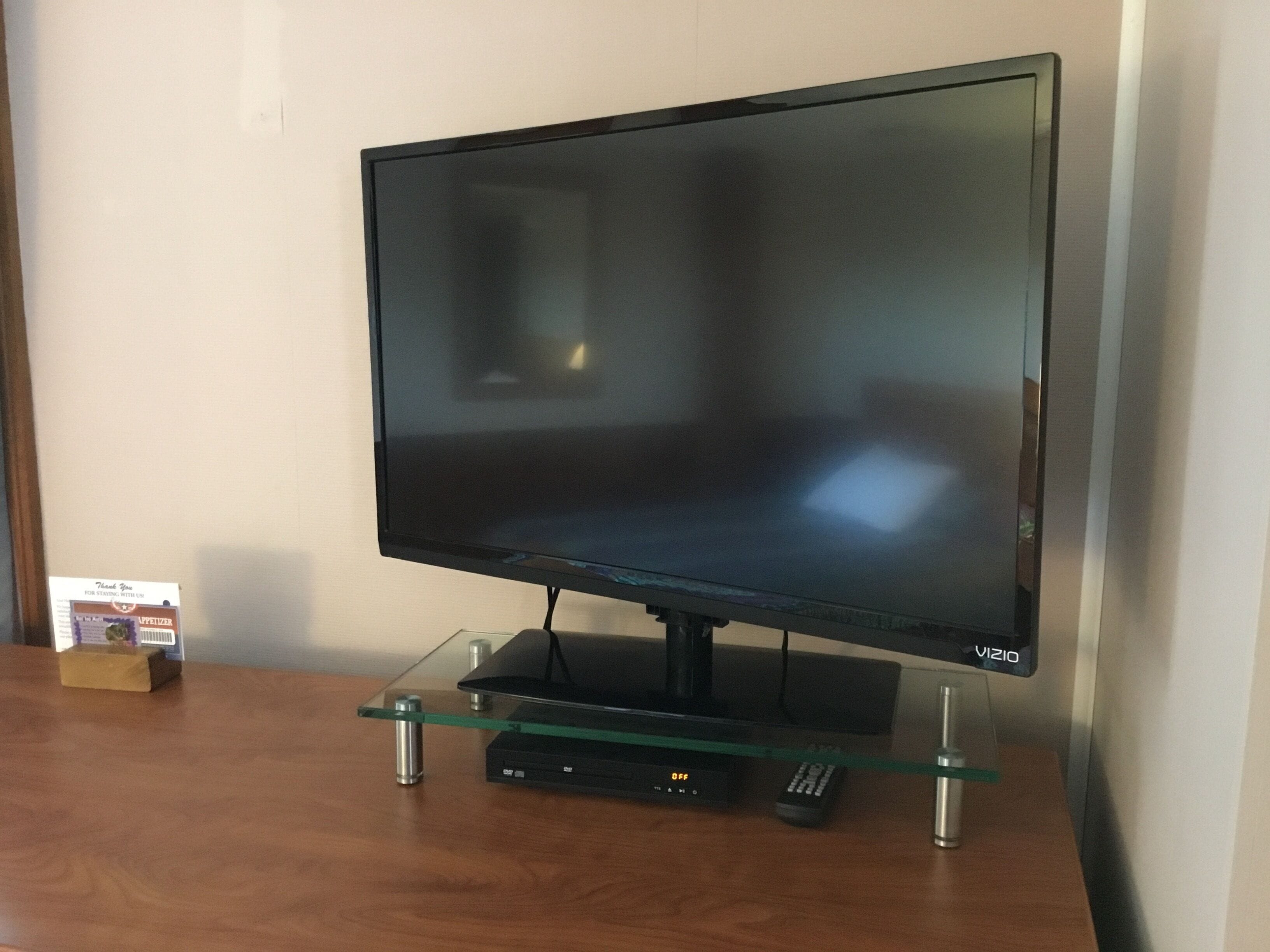 A flat-screen TV on a glass stand with a remote control.