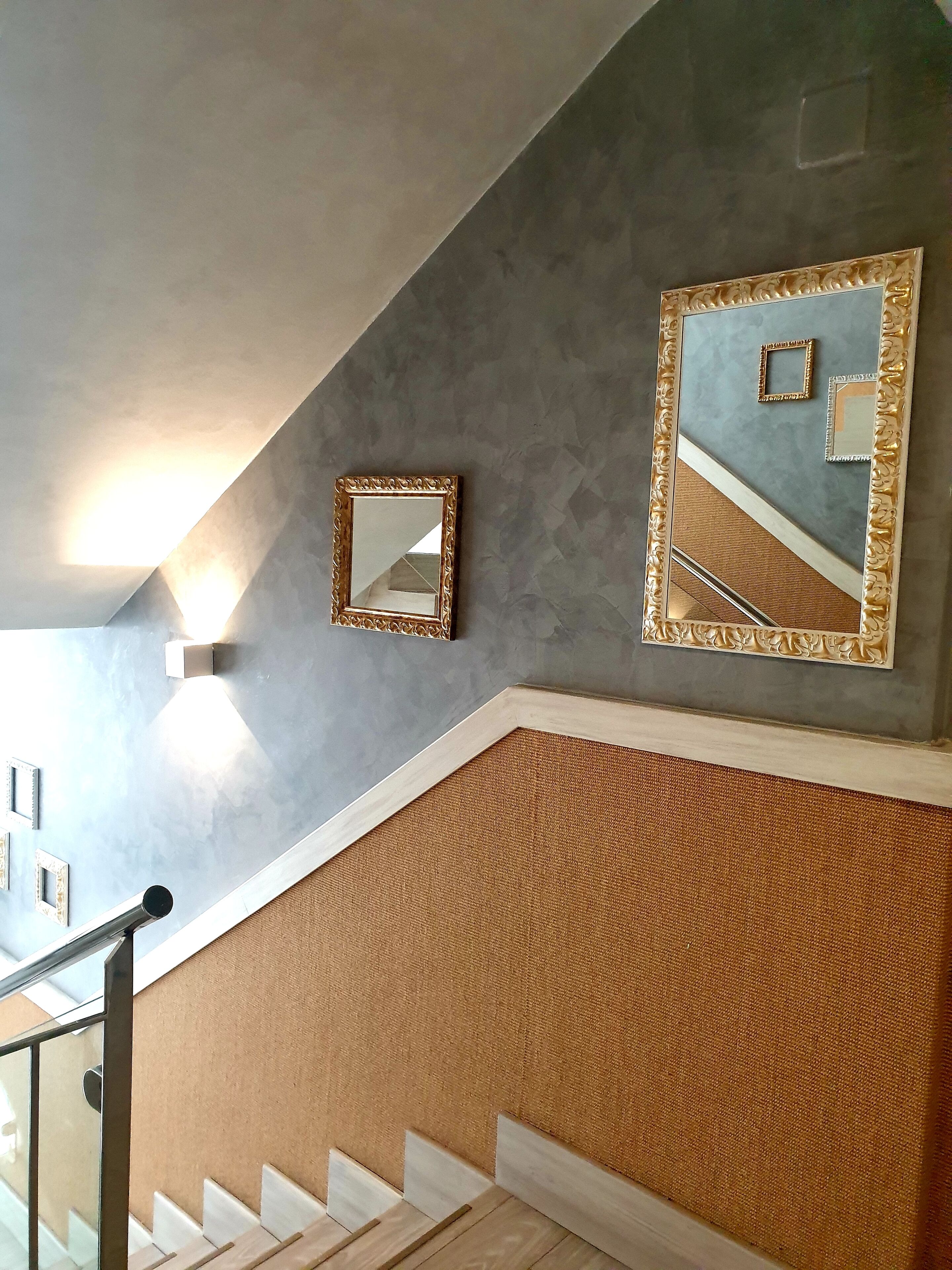 A staircase with a textured wall and a large mirror.