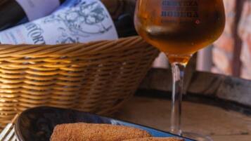 Un got de cervesa, una cistella de botelles de vi i dues croquetes sobre un plat.