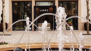 Una fuente con chorros de agua frente a una tienda llamada LOEWE.