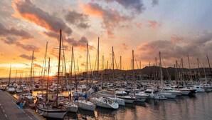Un puerto deportivo lleno de veleros al atardecer.