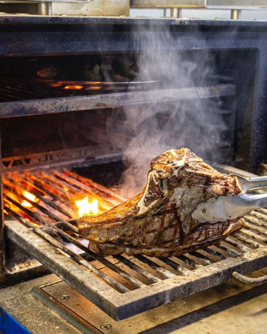A large piece of meat being grilled over an open flame.