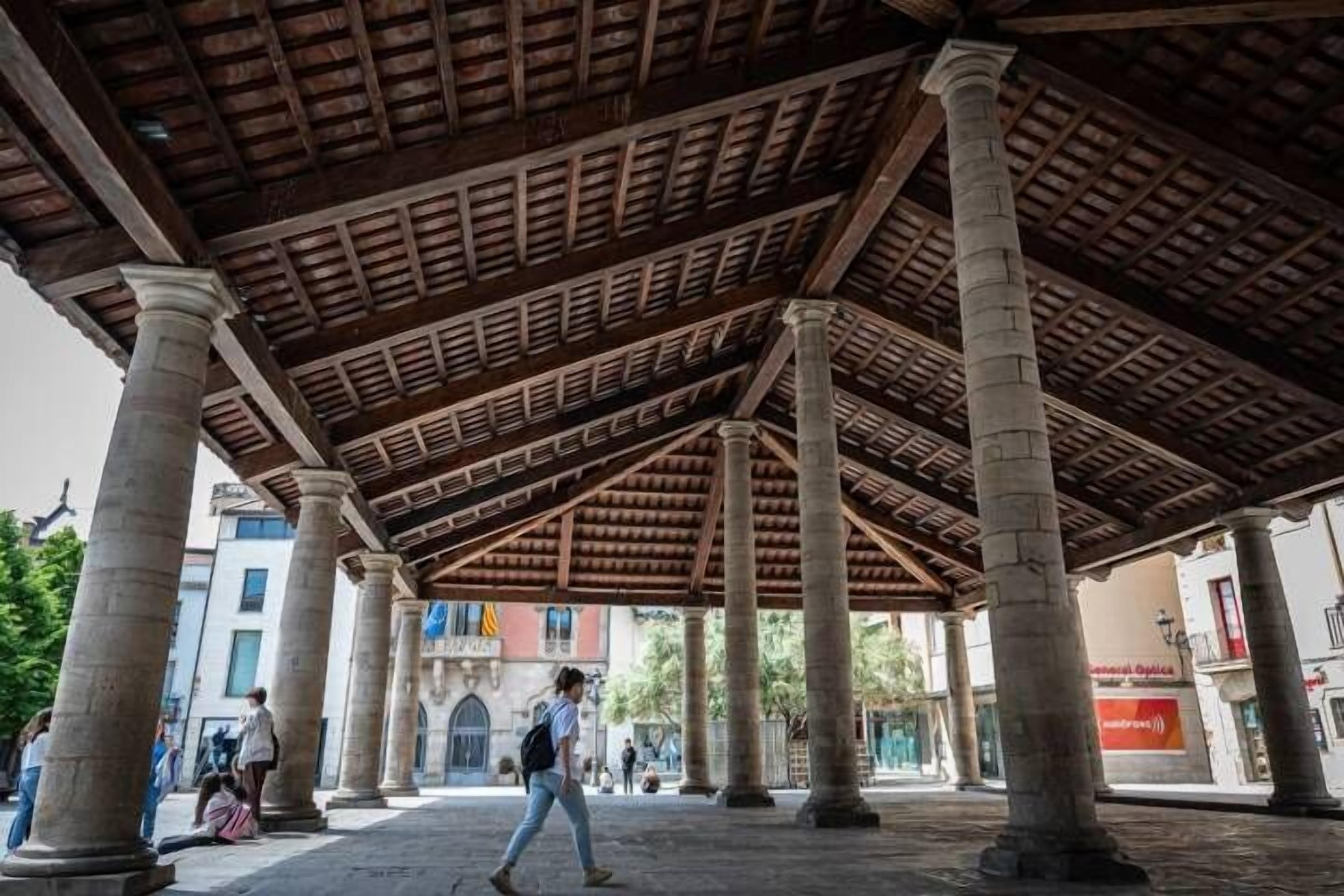 A covered outdoor area with columns and a wooden ceiling.