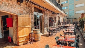 Un área de comedor al aire libre con paredes de piedra, muebles de madera y un ambiente rústico.