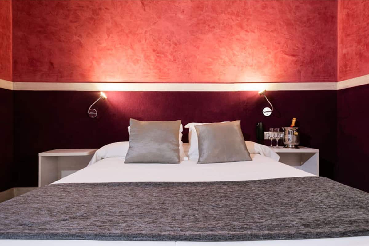 Una habitación de hotel con una cama grande, dos mesitas de noche y un minibar.