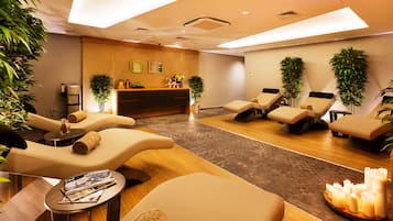 Ein Wellnessraum mit Massagesesseln, einer Rezeption und Pflanzen.