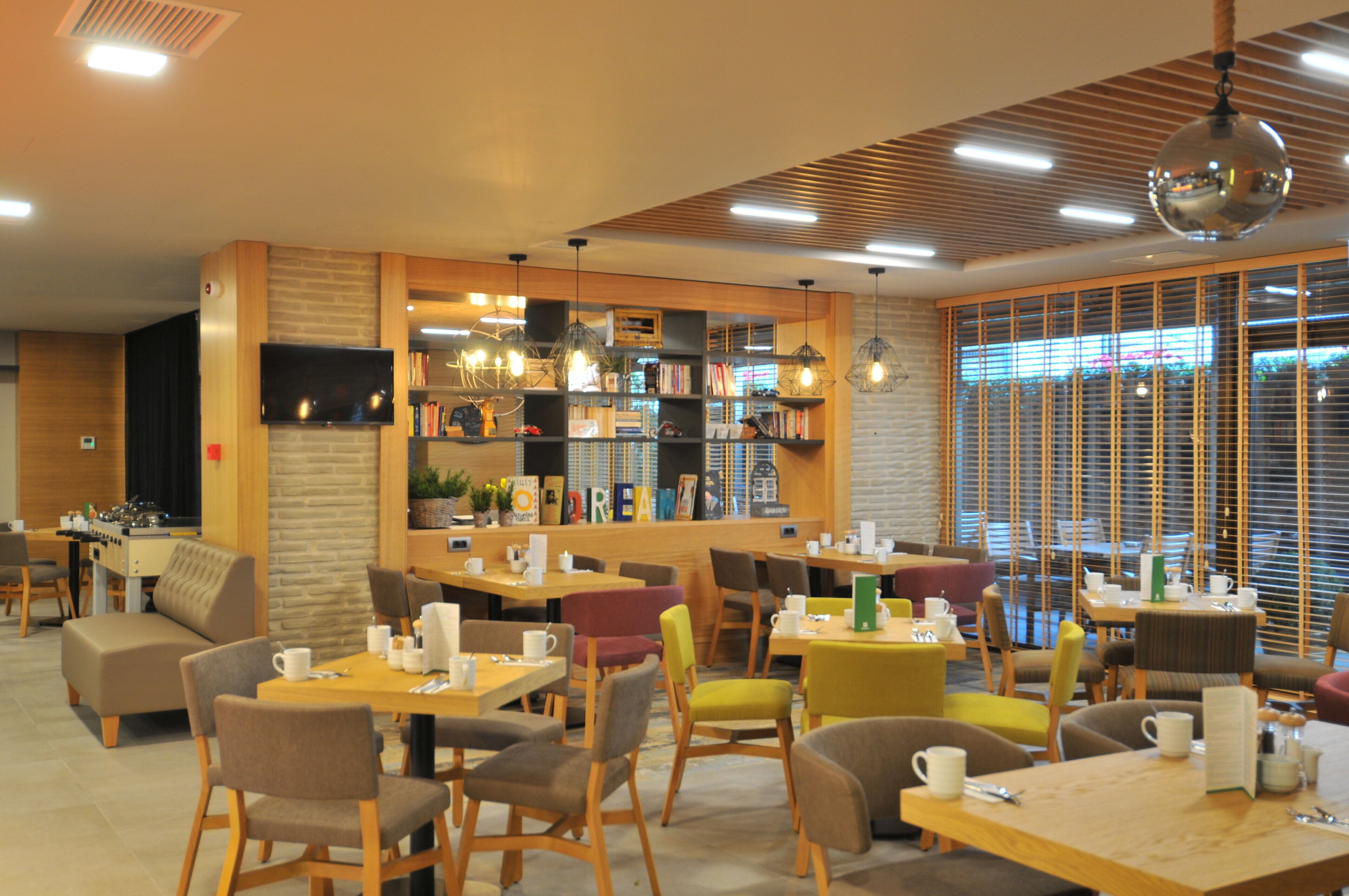 Un café moderno con varias zonas de estar, una barra de café y una estantería llena de libros.