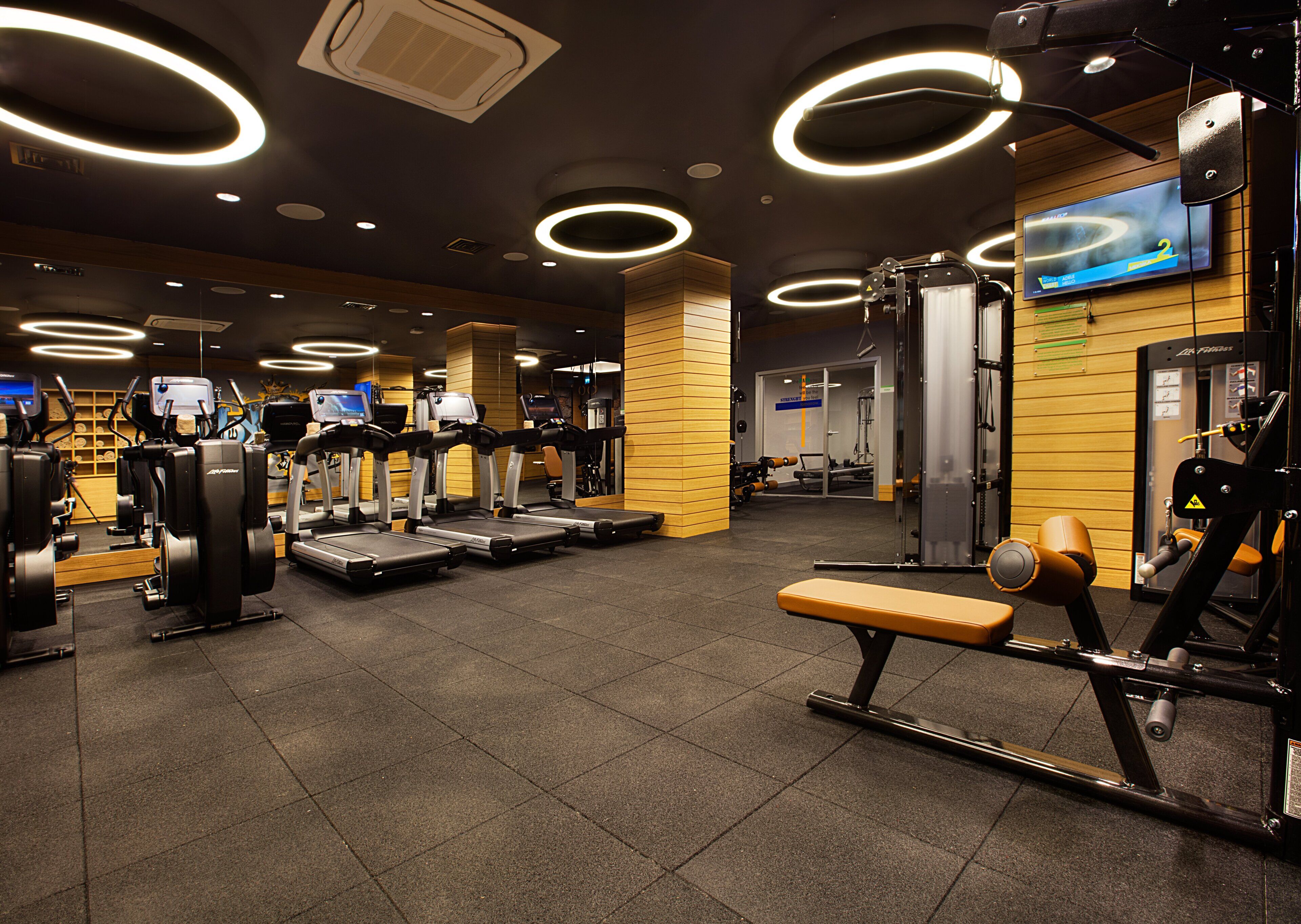 Ein modernes Fitnessstudio mit Laufbändern, Crosstrainern und Gewichten.