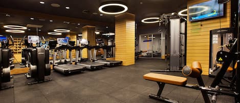 Ein modernes Fitnessstudio mit Laufbändern, Crosstrainern und Gewichten.