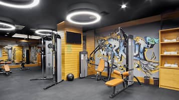 A gym with exercise equipment, a mirror, and a graffiti wall.