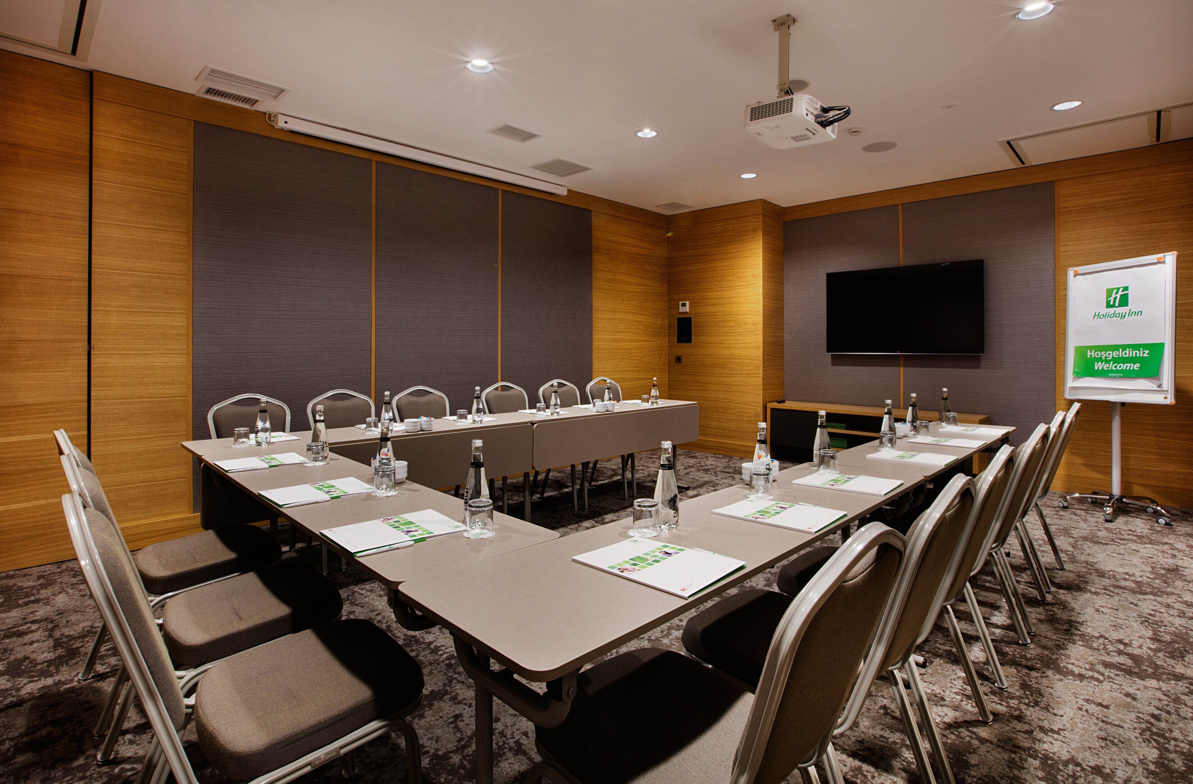A conference room with a long table, chairs, a projector, and a screen.