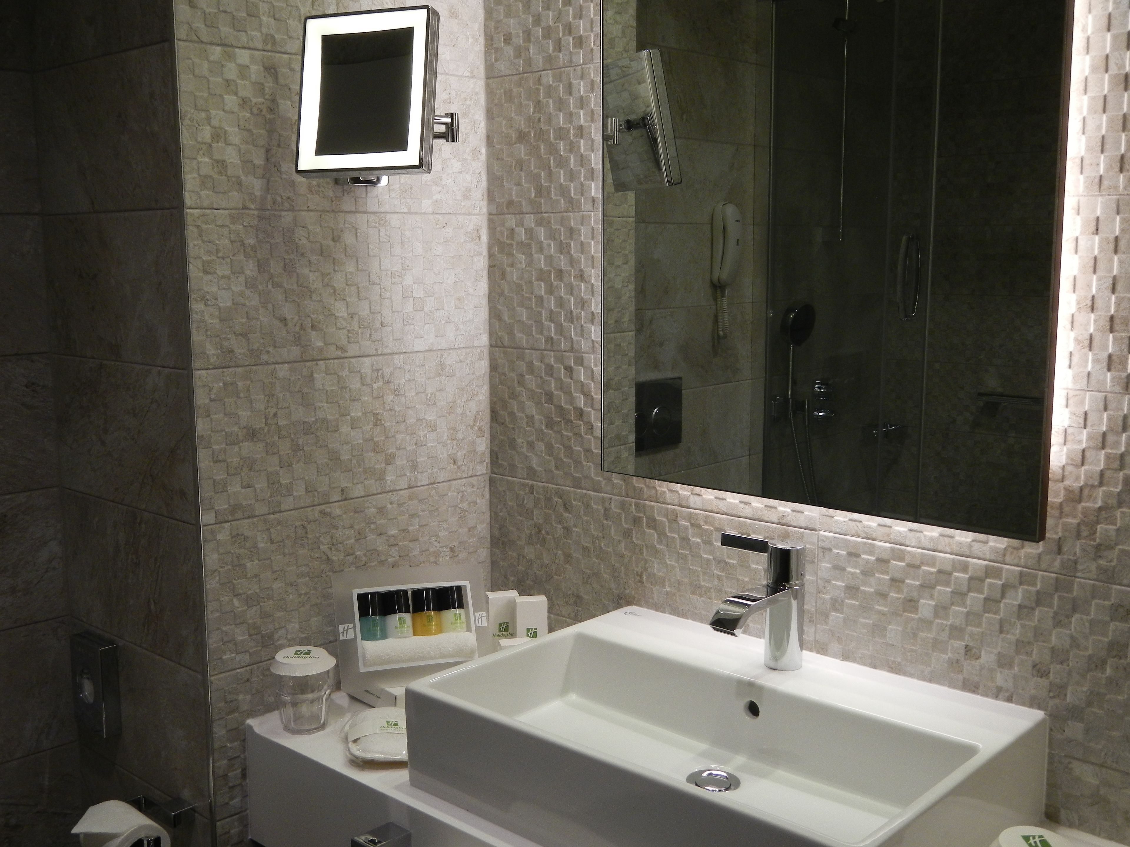 A bathroom with a white sink, a mirror, and a shower area.