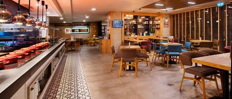 Interior de restaurante con zona de bar, asientos y suelo estampado.