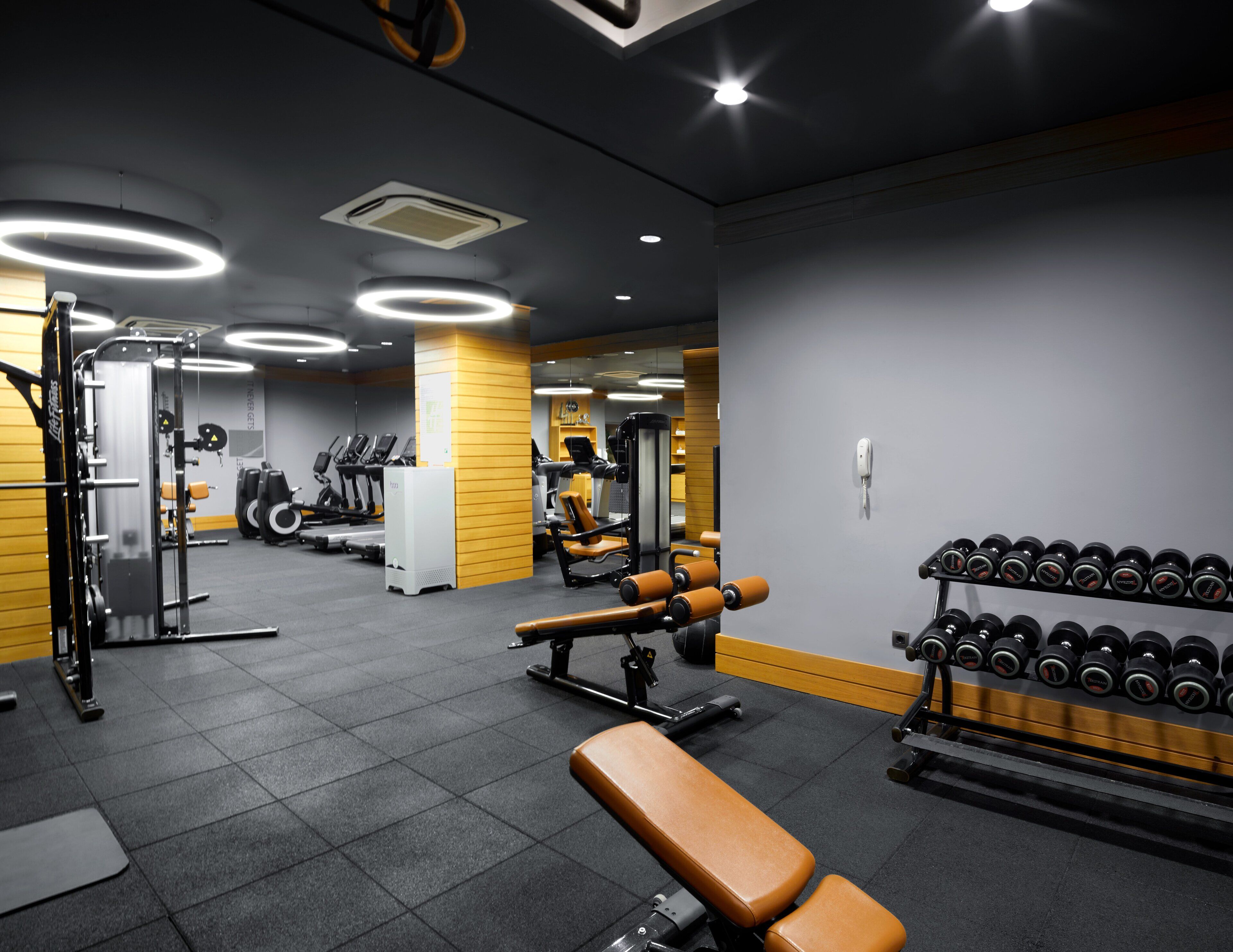 A gym with exercise equipment, treadmills, and dumbbells.