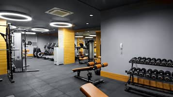 A gym with exercise equipment, treadmills, and dumbbells.