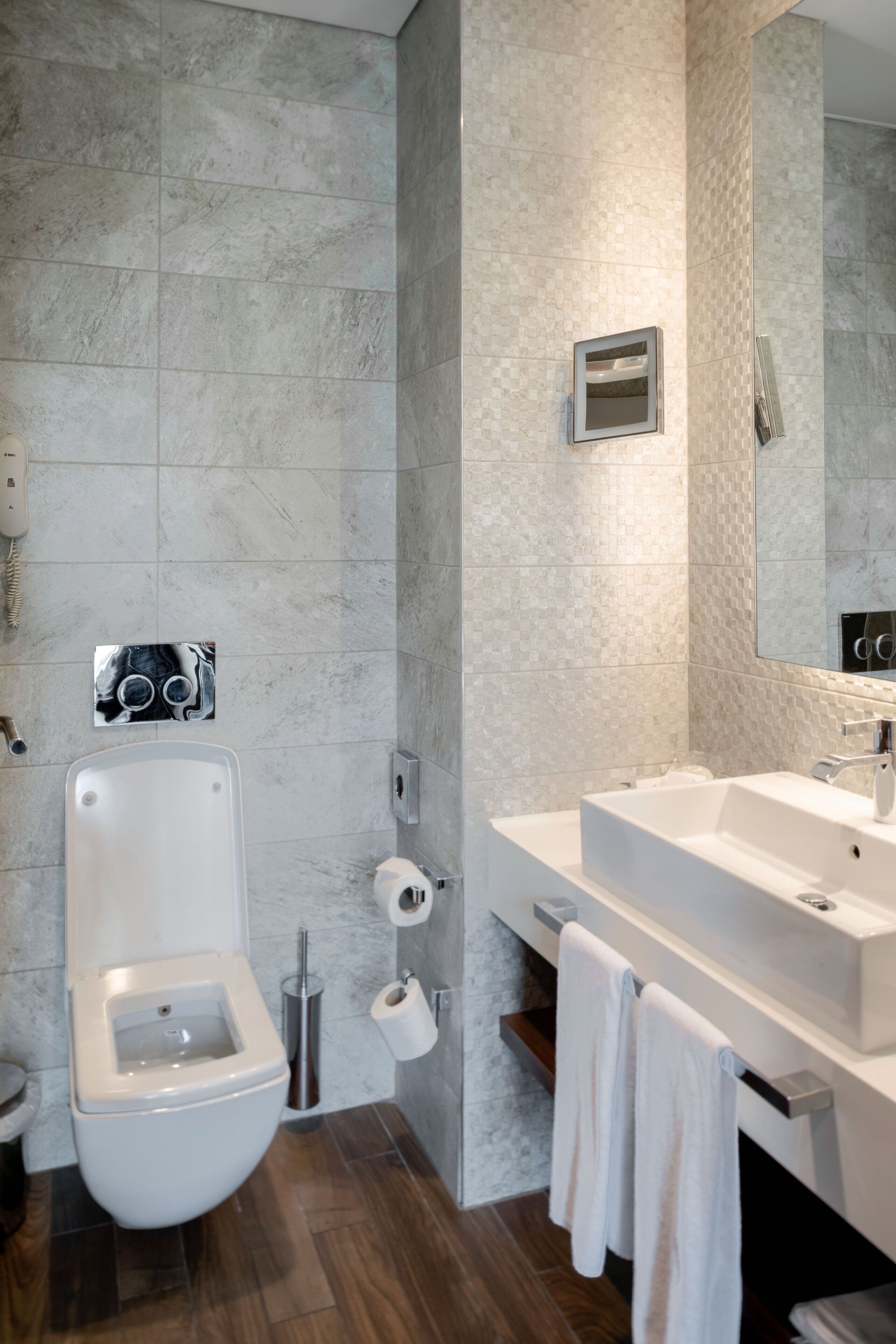 Un baño moderno con inodoro, bidé y un lavamanos grande con espejo.