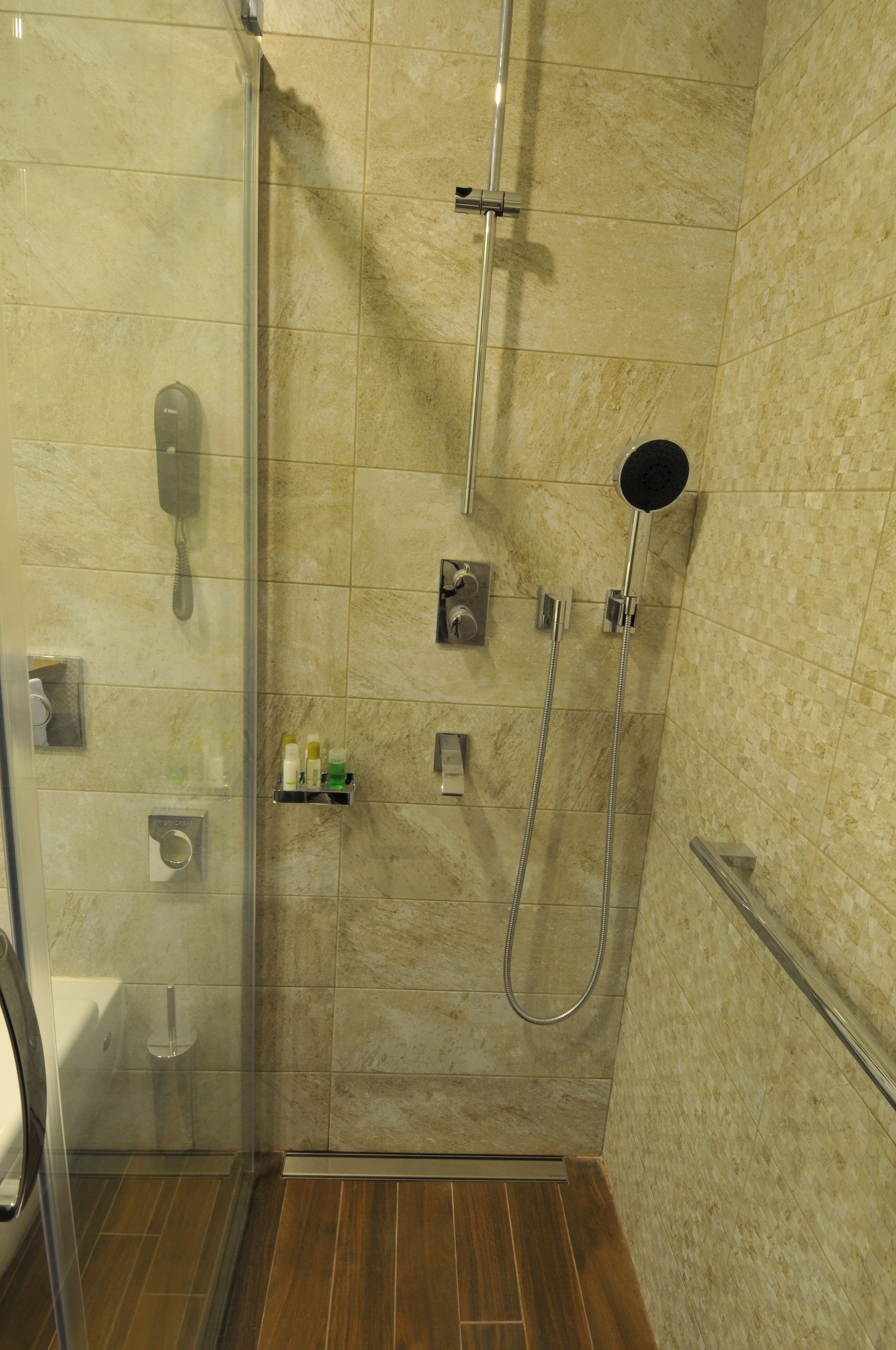 A glass-enclosed shower stall with a handheld showerhead and a wall-mounted faucet.