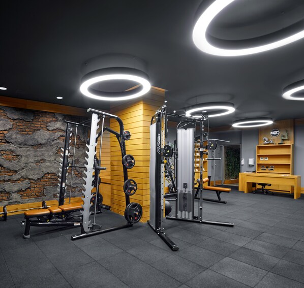 Een moderne sportschool met gewichthefapparatuur, banken en een houten wand.