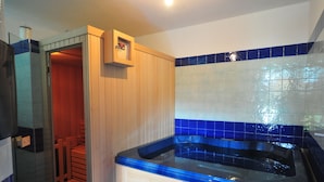 Ein Badezimmer mit Duschkabine aus Glas, einem Holzschrank und einer Wand mit blauen Fliesen.
