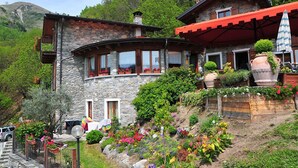 Ein Steinhaus mit Balkon, umgeben von bunten Blumen und Pflanzen.