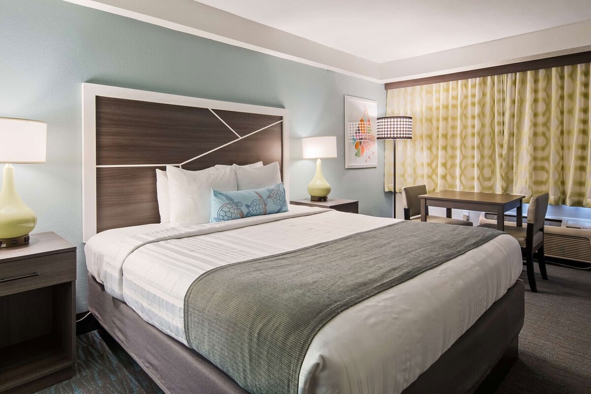 A hotel room with a bed, bedside tables, a desk, and a chair.