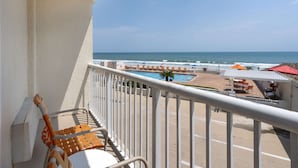 A balcony with a view of the beach and pool area.