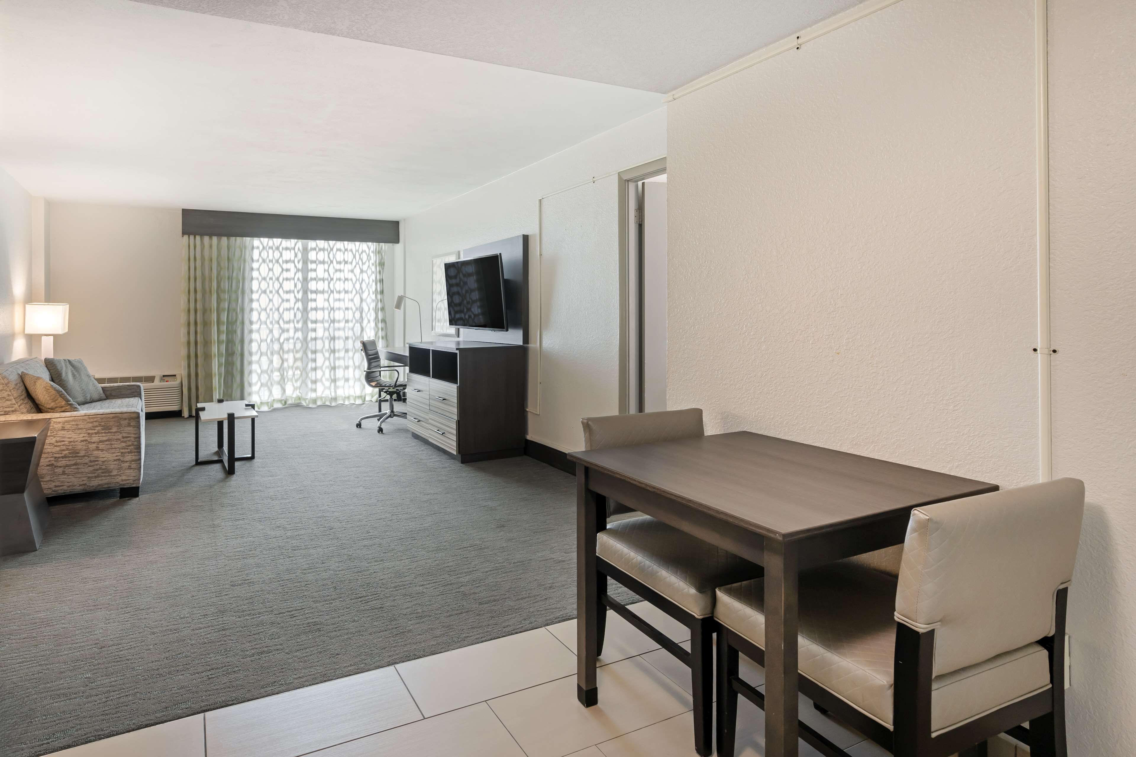 Una habitación de hotel con una mesa de comedor, un sofá, un televisor y un escritorio.