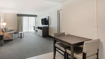 Una habitación de hotel con una mesa de comedor, un sofá, un televisor y un escritorio.
