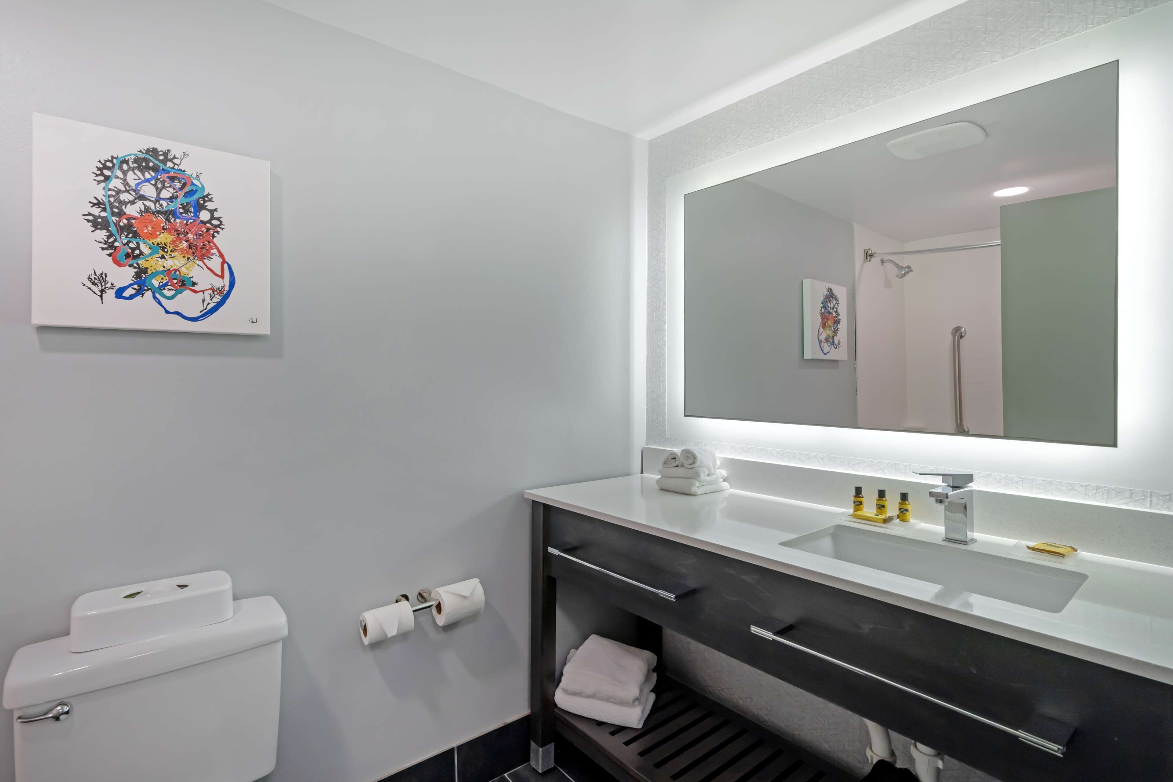 A modern bathroom with a white toilet, a sink with a mirror above it, and a towel rack.