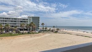 A beach view with a hotel in the background.