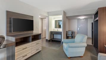 Una sala de estar moderna con un televisor de pantalla plana, un mueble bajo de madera y un sillón azul claro.