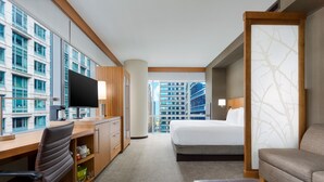 A hotel room with a large bed, a desk with a chair, a sofa, and a TV. - Hyatt Place Chicago/Downtown - The Loop (Chicago)