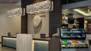 A reception area with a modern design, including a reception desk, a decorative wall, and a display case with snacks. - Hyatt Place Chicago/Downtown - The Loop (Chicago)