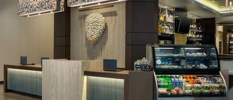 A reception area with a modern design, including a reception desk, a decorative wall, and a display case with snacks.