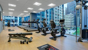 A gym with cardio machines, weight benches, and a large window offering a city view. - Hyatt Place Chicago/Downtown - The Loop (Chicago)