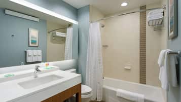 A bathroom with a sink, mirror, toilet, and bathtub.