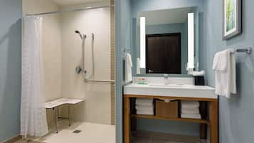 Un baño moderno con ducha, lavamanos y espejo.