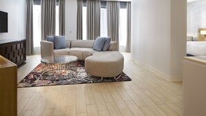 Una sala moderna con un sofá modular, una mesa de centro de vidrio y una alfombra estampada.