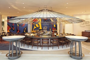 A bar area with a round table, stools, and a large abstract painting on the wall.