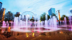 A fountain with water jets, a Ferris wheel, and modern buildings in the background. - Hotel Indigo Atlanta Downtown by IHG (Atlanta)