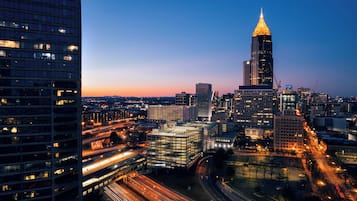 A cityscape at dusk with illuminated skyscrapers and a prominent building with a spire.