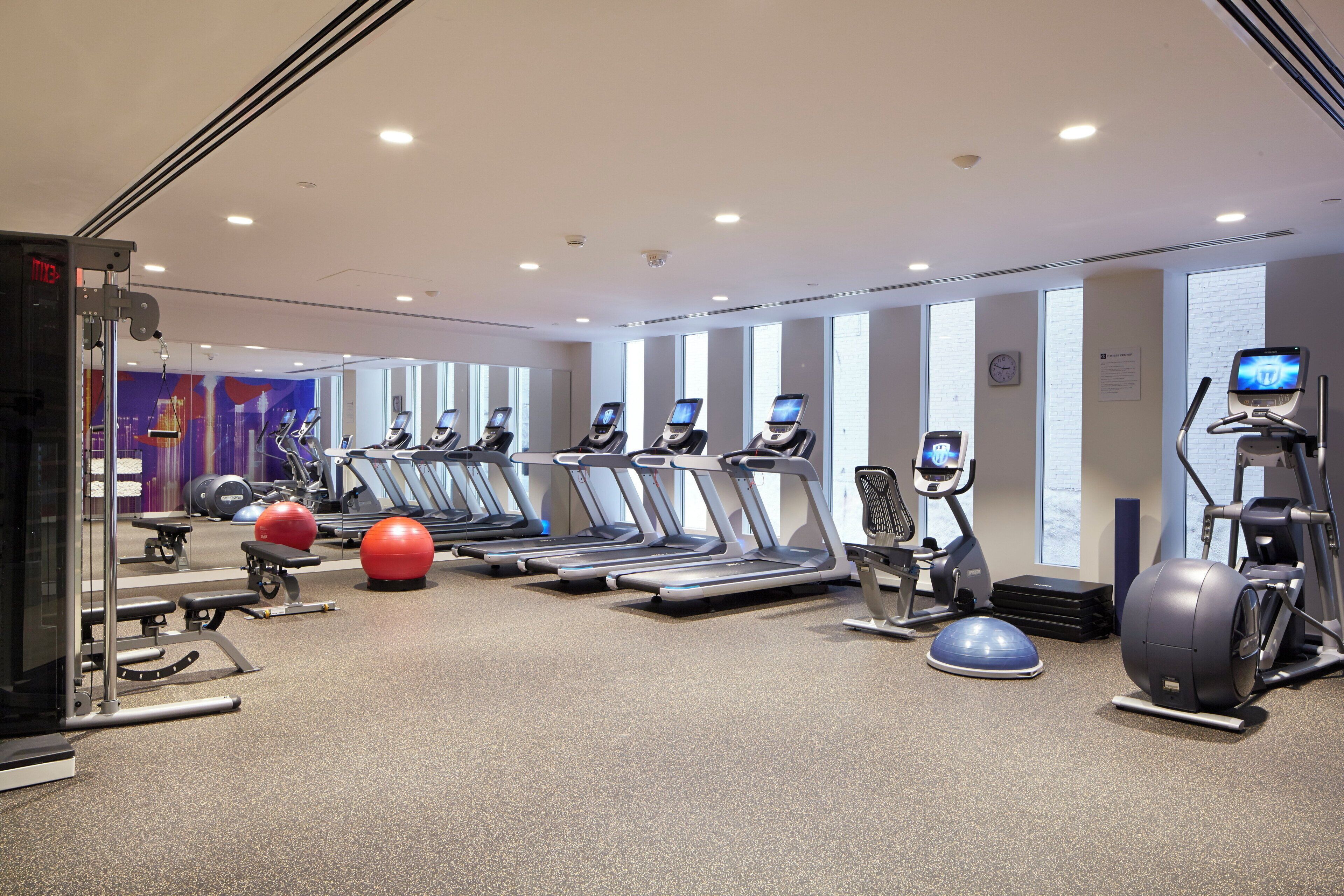 Academia com esteiras, elípticos e bolas de exercício.