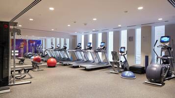 Academia com esteiras, elípticos e bolas de exercício.