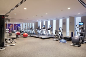 A gym with treadmills, elliptical machines, and exercise balls.